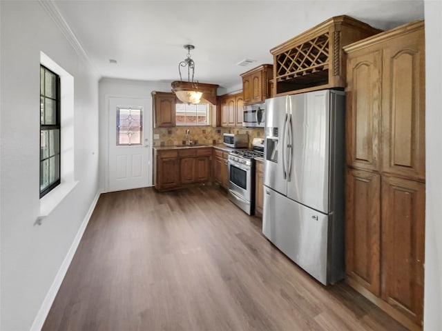 kitchen featuring pendant lighting, sink, tasteful backsplash, appliances with stainless steel finishes, and hardwood / wood-style floors