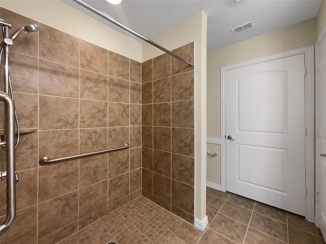 bathroom with tiled shower and tile patterned flooring