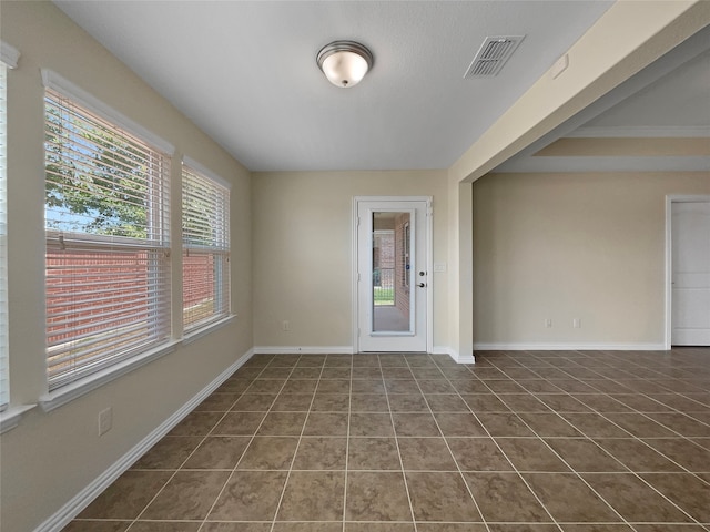 tiled spare room with a healthy amount of sunlight and crown molding