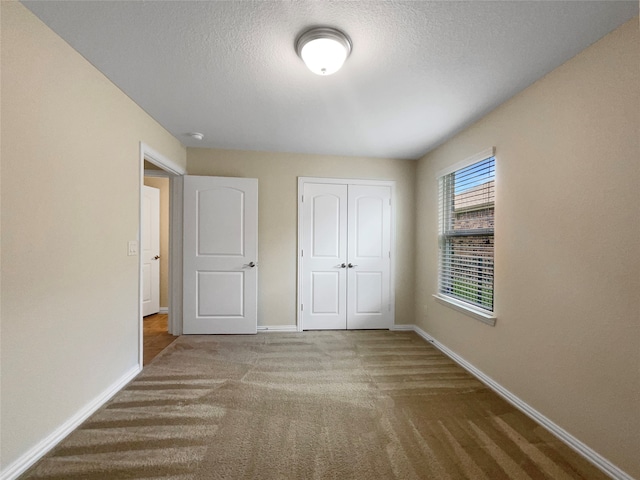 unfurnished bedroom featuring carpet floors, a textured ceiling, and a closet