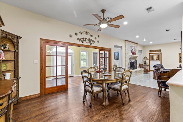 dining space with ceiling fan, a fireplace, dark wood-type flooring, and french doors