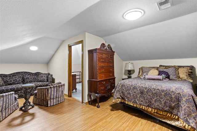 bedroom featuring hardwood / wood-style floors, a textured ceiling, and lofted ceiling