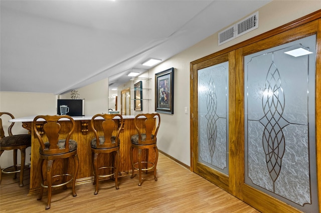 bar with light hardwood / wood-style floors and vaulted ceiling