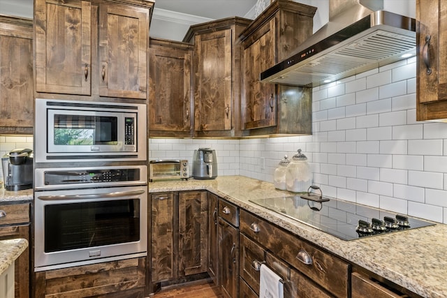 kitchen featuring wall chimney exhaust hood, stainless steel appliances, light stone counters, and decorative backsplash