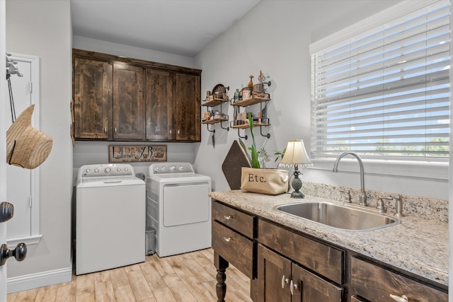 clothes washing area featuring washer and clothes dryer, cabinets, sink, and light hardwood / wood-style floors