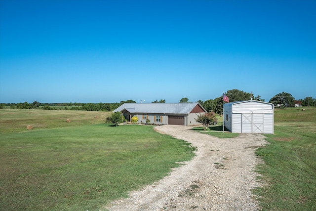 view of front of house with a storage unit, a front yard, a rural view, and a garage