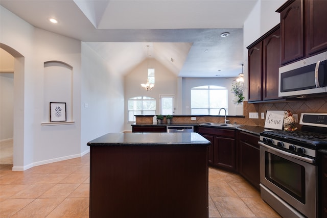 kitchen with backsplash, sink, vaulted ceiling, appliances with stainless steel finishes, and a kitchen island