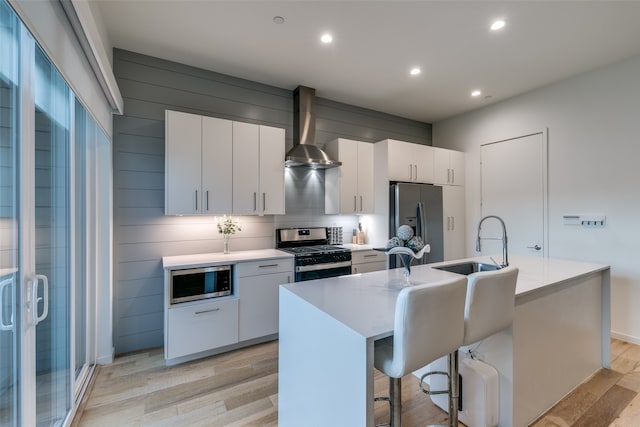 kitchen featuring light hardwood / wood-style flooring, an island with sink, appliances with stainless steel finishes, and white cabinetry