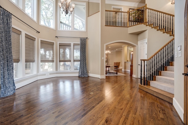 foyer featuring a towering ceiling, dark wood-type flooring, a chandelier, and a healthy amount of sunlight