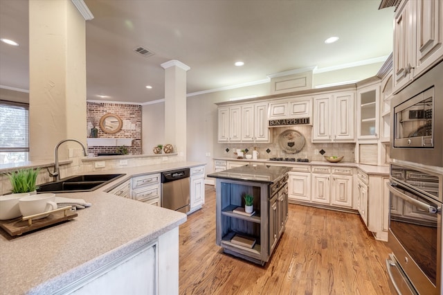 kitchen with ornamental molding, sink, kitchen peninsula, appliances with stainless steel finishes, and light wood-type flooring