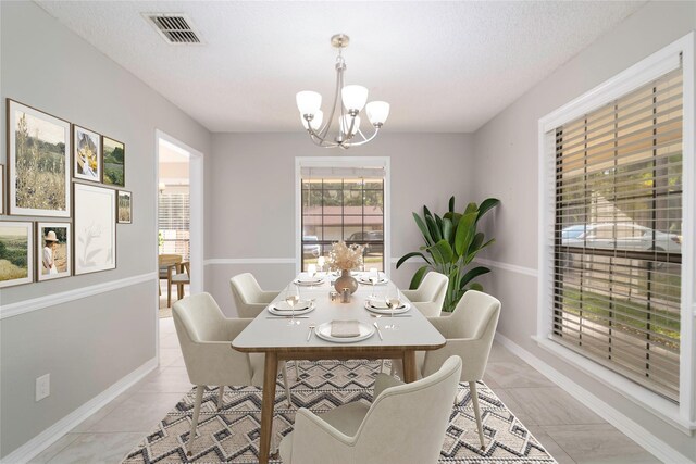 dining room with a textured ceiling, a notable chandelier, and light tile patterned flooring