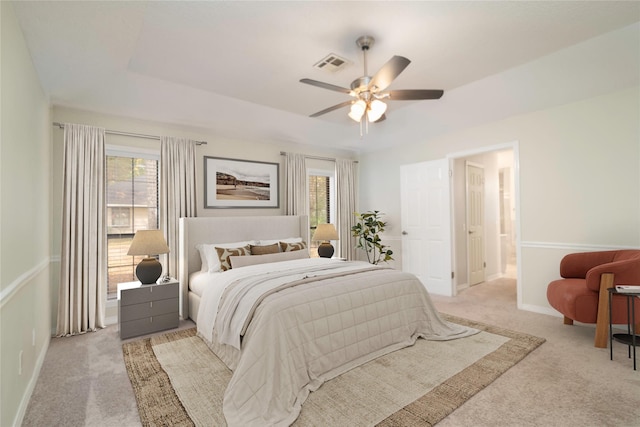 carpeted bedroom featuring a raised ceiling and ceiling fan