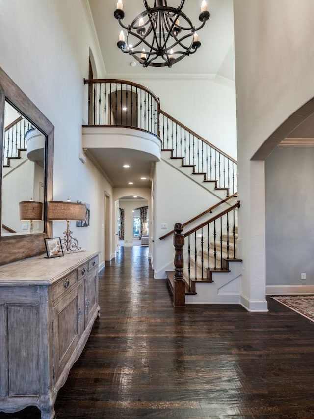 foyer entrance featuring stairway, arched walkways, and crown molding