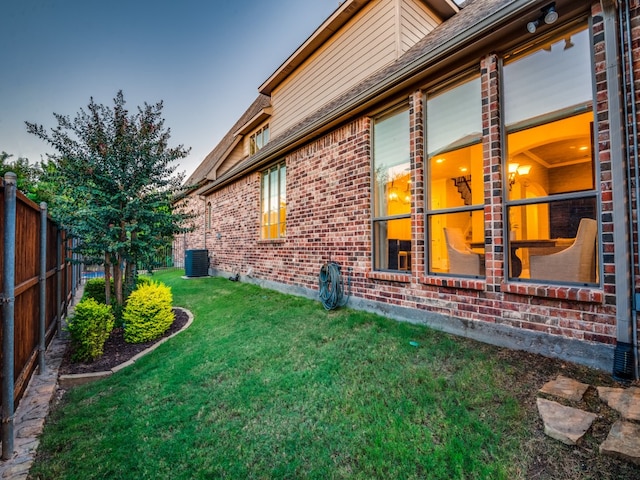 property exterior at dusk featuring central AC unit and a lawn