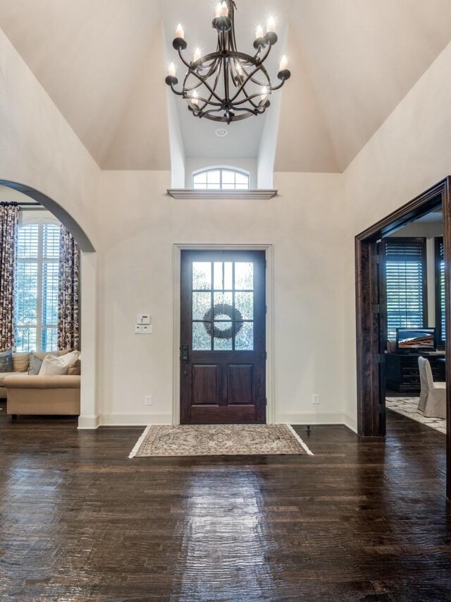 foyer entrance featuring high vaulted ceiling, dark hardwood / wood-style floors, and a chandelier