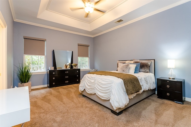 bedroom featuring ceiling fan, a tray ceiling, light carpet, and ornamental molding