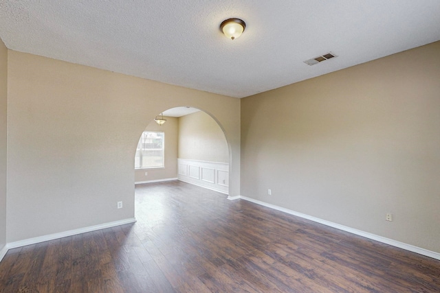 empty room with a textured ceiling and dark hardwood / wood-style flooring