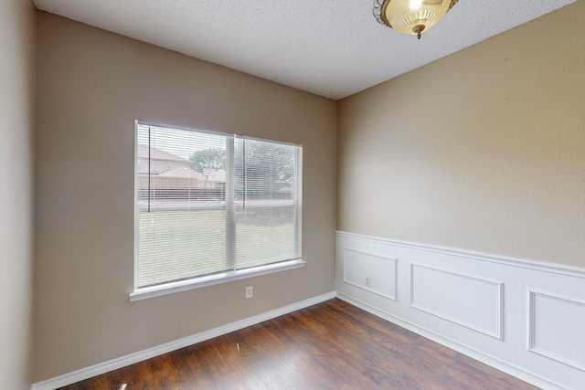 unfurnished room featuring a textured ceiling and dark hardwood / wood-style flooring