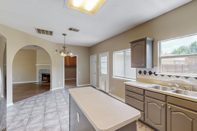 kitchen featuring a fireplace, plenty of natural light, a chandelier, and a center island