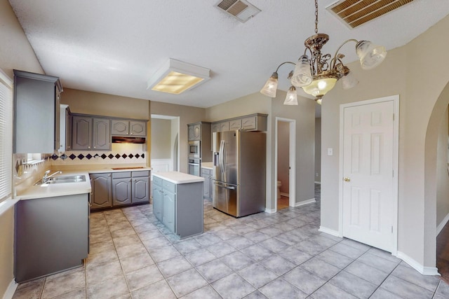 kitchen with an inviting chandelier, appliances with stainless steel finishes, a center island, and gray cabinets