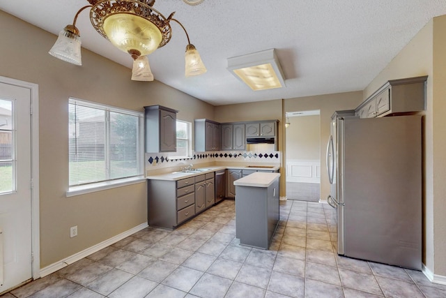 kitchen featuring a textured ceiling, a center island, sink, gray cabinetry, and appliances with stainless steel finishes