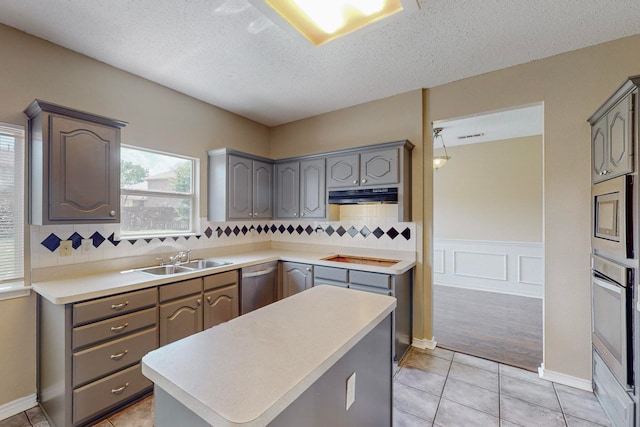 kitchen with gray cabinets, stainless steel appliances, sink, and a textured ceiling