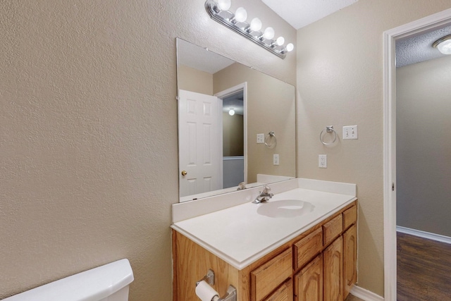 bathroom with vanity, a textured ceiling, hardwood / wood-style floors, and toilet