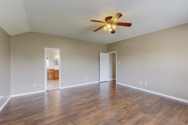 spare room featuring a textured ceiling, lofted ceiling, dark wood-type flooring, and ceiling fan