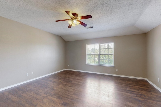 empty room with a textured ceiling, lofted ceiling, dark wood-type flooring, and ceiling fan