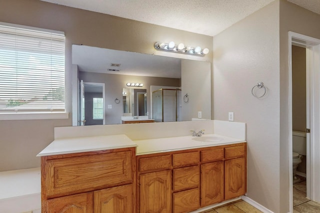 bathroom with a textured ceiling, vanity, toilet, and an enclosed shower