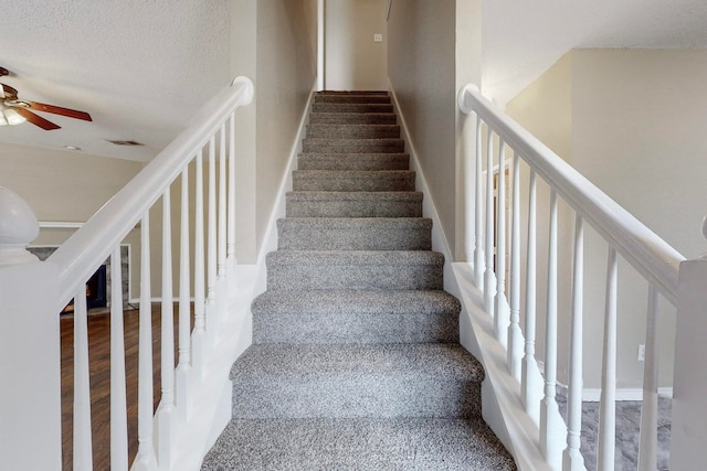 staircase with a textured ceiling, hardwood / wood-style floors, and ceiling fan