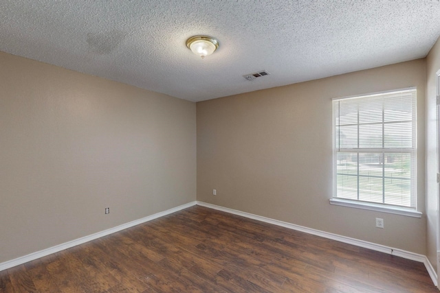 empty room with a textured ceiling and dark wood-type flooring