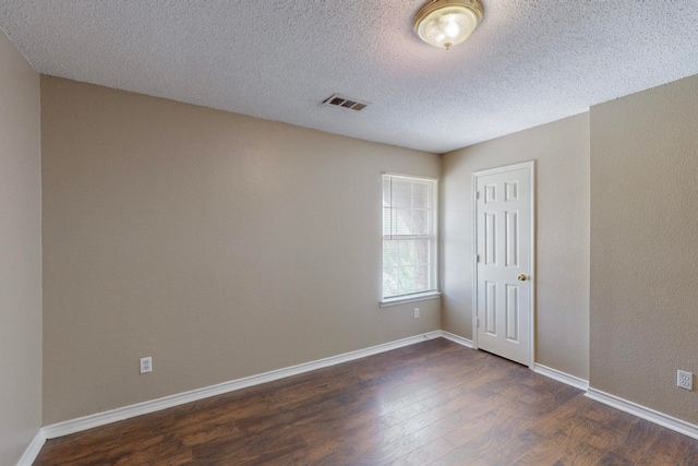 empty room featuring a textured ceiling and dark hardwood / wood-style floors