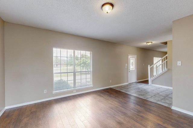 unfurnished room with a textured ceiling and dark hardwood / wood-style flooring