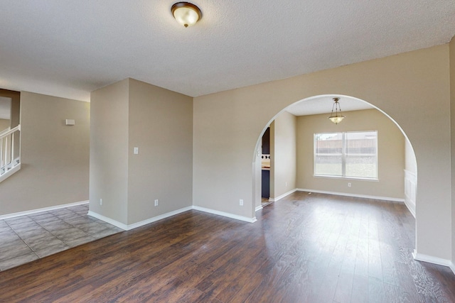 spare room with a textured ceiling and dark wood-type flooring