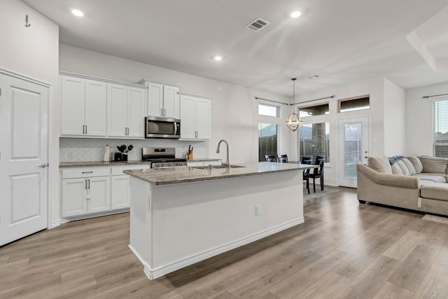 kitchen featuring sink, white cabinets, an island with sink, and appliances with stainless steel finishes