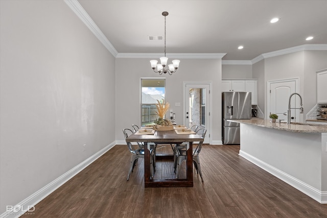 dining room with ornamental molding, dark hardwood / wood-style floors, a chandelier, and sink