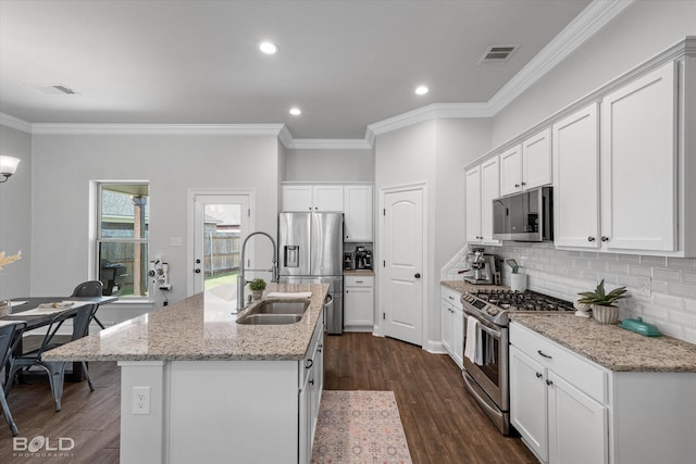 kitchen featuring appliances with stainless steel finishes, white cabinetry, dark wood-type flooring, an island with sink, and sink