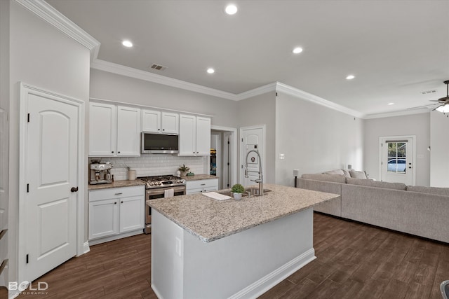 kitchen with white cabinetry, dark wood-type flooring, an island with sink, stainless steel appliances, and ceiling fan