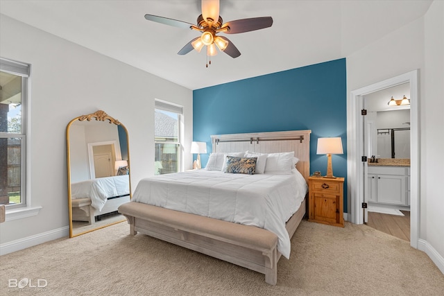 carpeted bedroom with multiple windows, ceiling fan, and ensuite bathroom