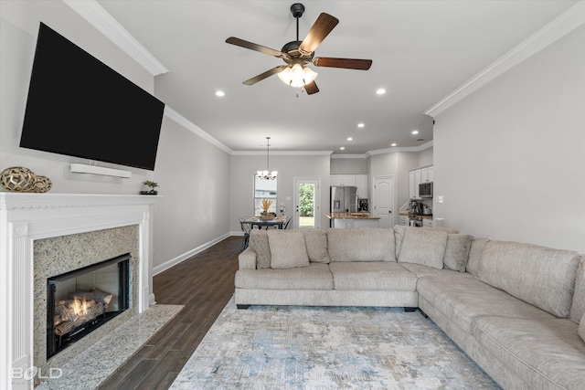 living room with ceiling fan with notable chandelier, ornamental molding, a high end fireplace, and hardwood / wood-style floors