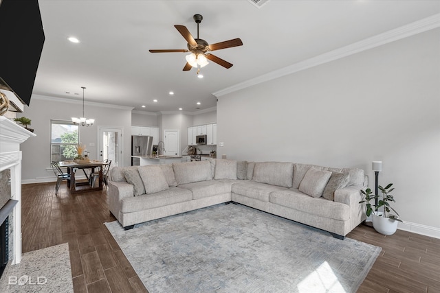 living room featuring sink, ceiling fan with notable chandelier, crown molding, and dark wood-type flooring