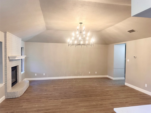 unfurnished living room featuring lofted ceiling, a textured ceiling, dark wood-type flooring, a notable chandelier, and a fireplace