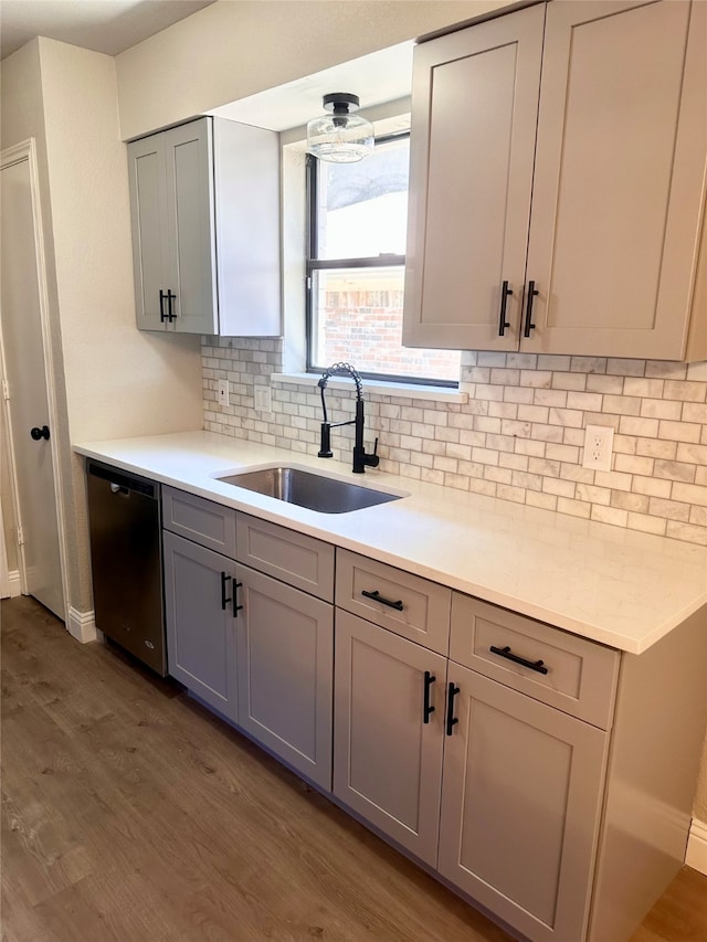 kitchen with gray cabinetry, stainless steel dishwasher, sink, and wood-type flooring