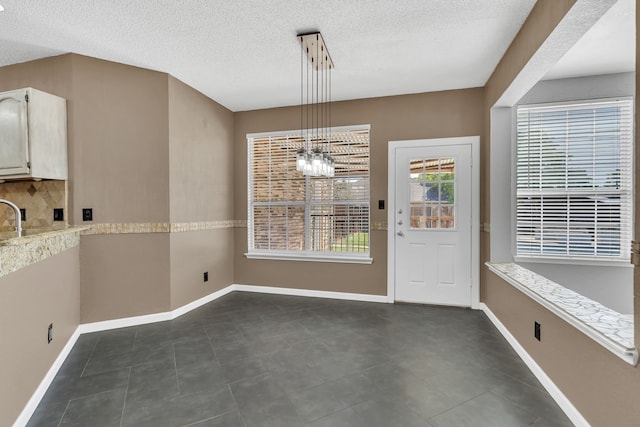 unfurnished dining area with a notable chandelier and a textured ceiling