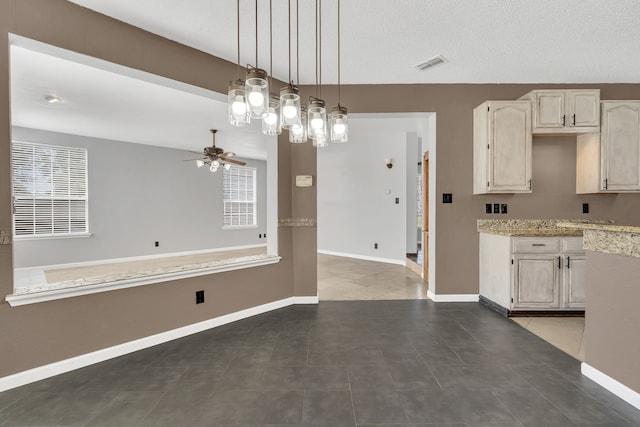 kitchen featuring cream cabinetry, ceiling fan, dark tile patterned floors, and decorative light fixtures