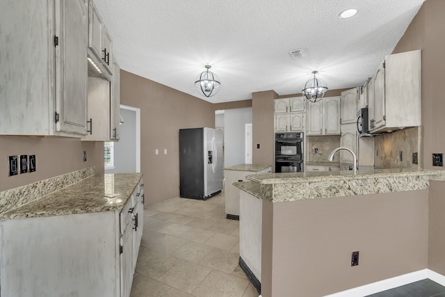 kitchen with a notable chandelier, kitchen peninsula, appliances with stainless steel finishes, and decorative light fixtures