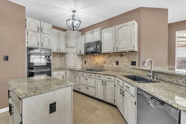 kitchen featuring light stone counters, hanging light fixtures, sink, black appliances, and a notable chandelier