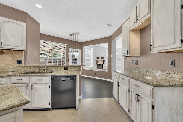 kitchen featuring hanging light fixtures, sink, a textured ceiling, dishwasher, and light stone countertops