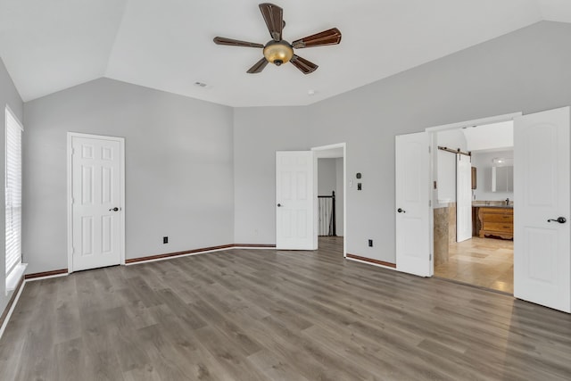 unfurnished bedroom featuring multiple windows, wood-type flooring, vaulted ceiling, and ceiling fan